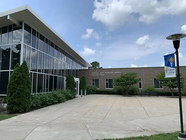 The front of a building with a sign in front of it advertising various programs.