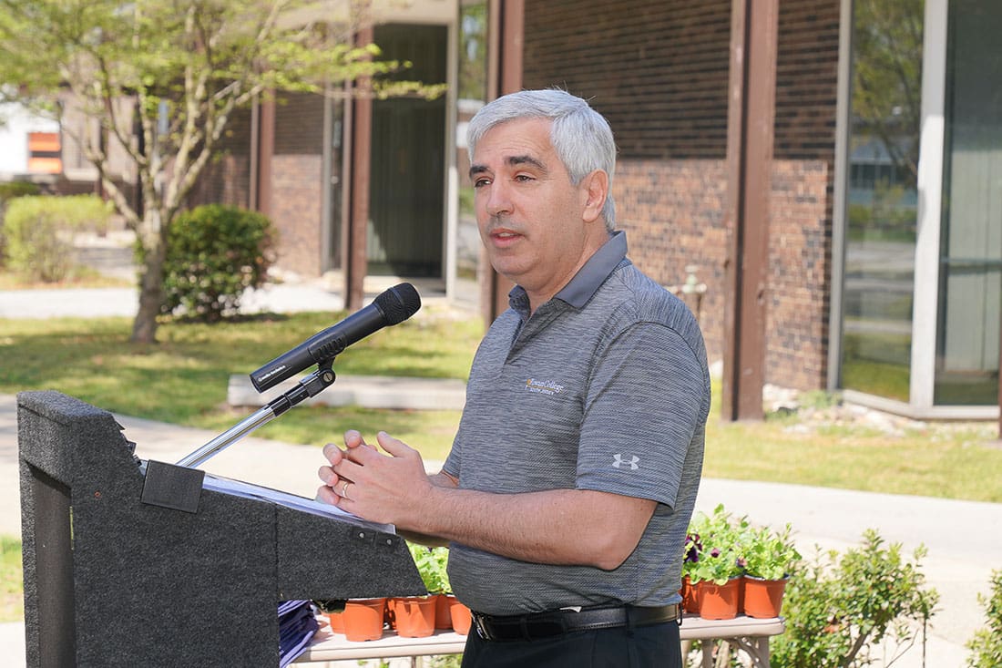 A man standing at a podium in front of a building.