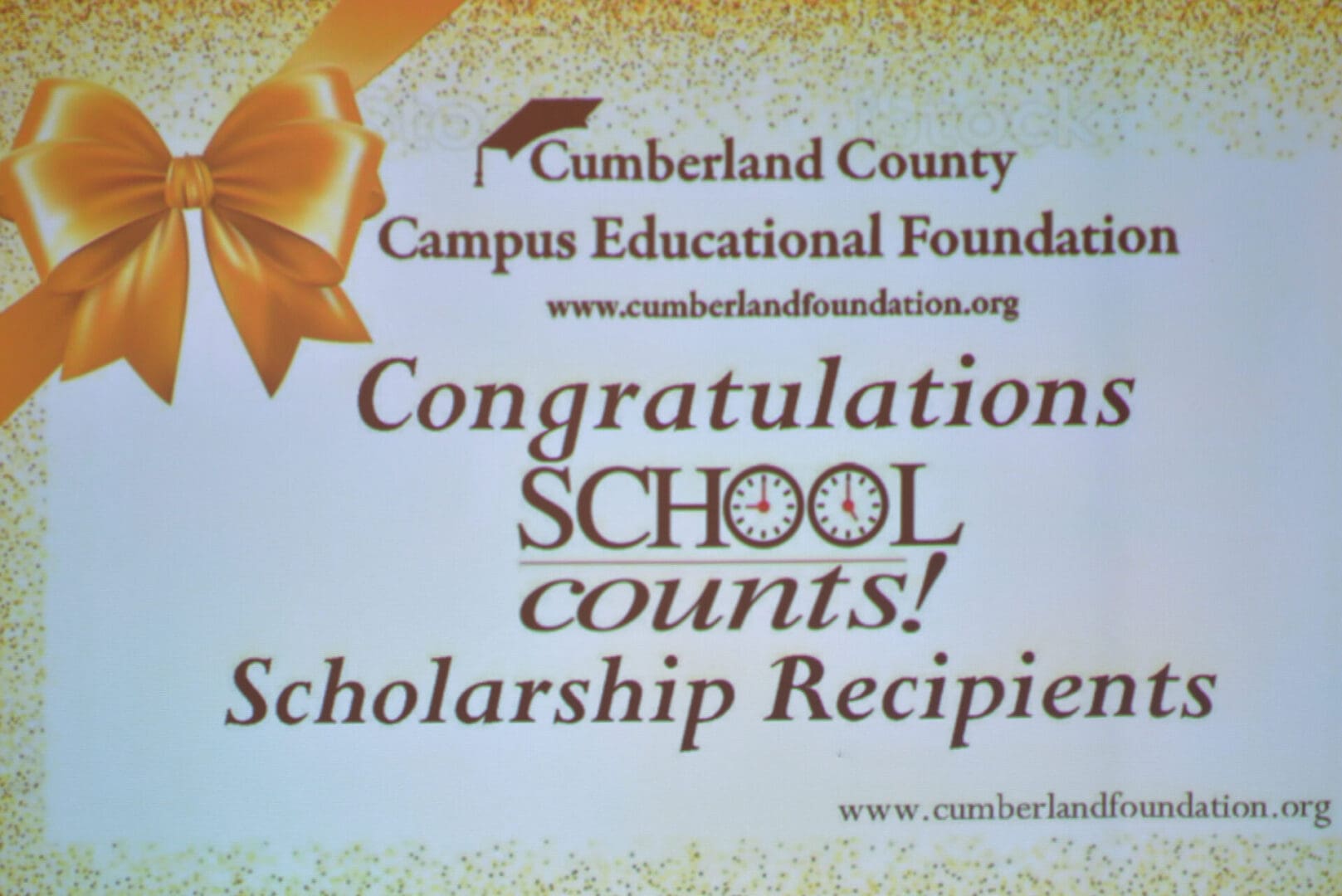 A projector screen displaying "congratulations school counts! scholarship recipients" with the cumberland campus educational foundation logo and website.