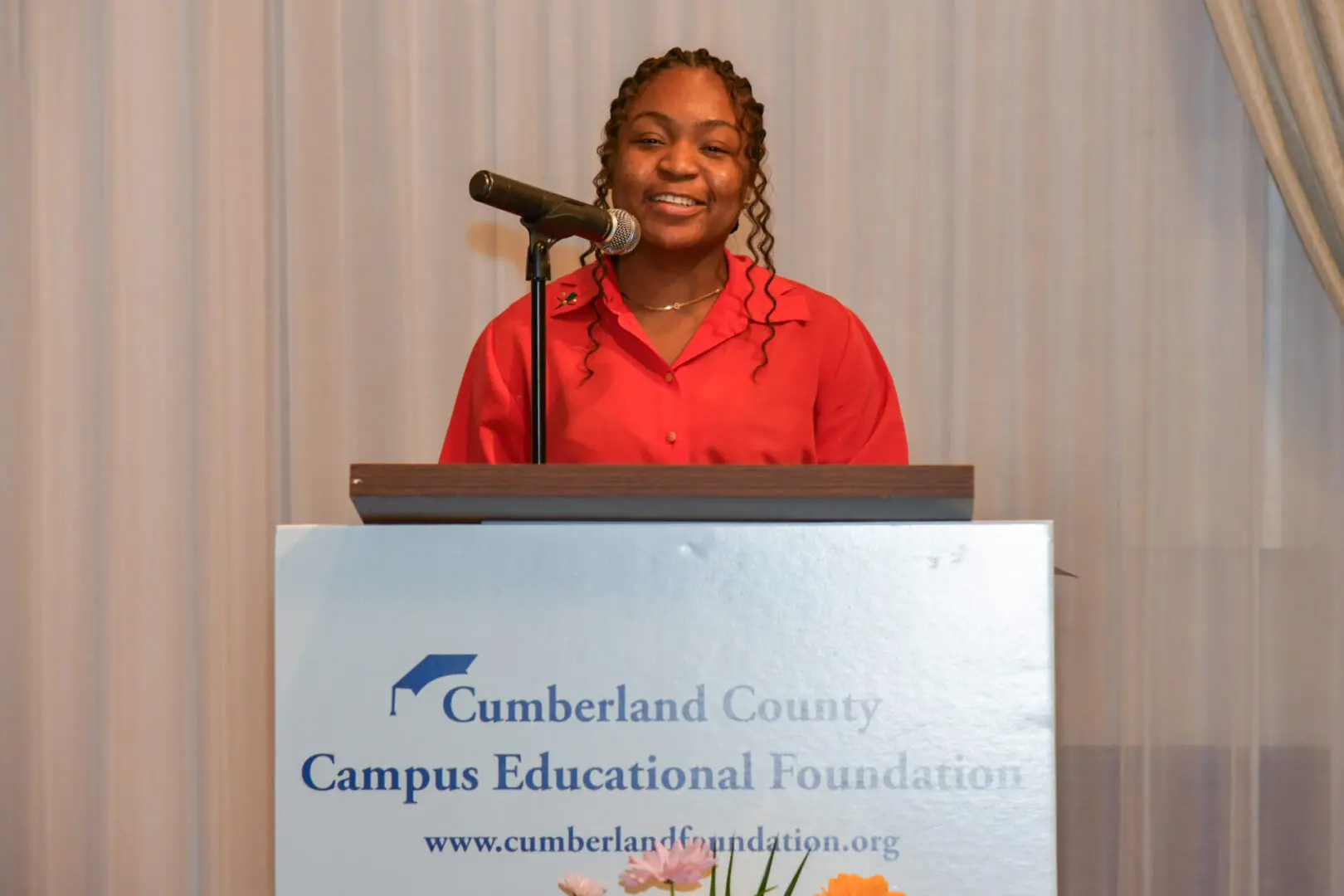 A smiling woman speaking at a podium for Cumberland County Campus Educational Foundation.