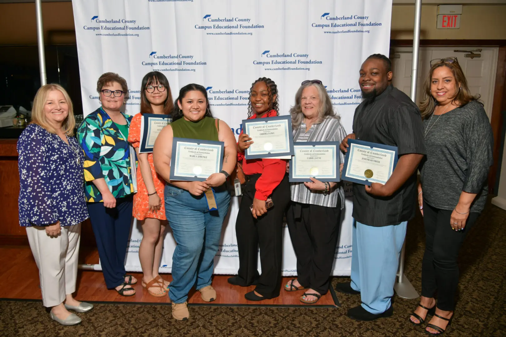 Group of six women standing with certificates, smiling at the camera indoors.