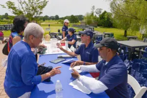 Officials in blue uniforms reviewing documents outdoors at a table.