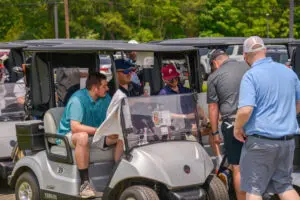 People gathered around a golf cart in a lush outdoor setting.
