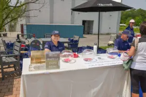 Volunteers at an outdoor event booth with informational materials and donations box.