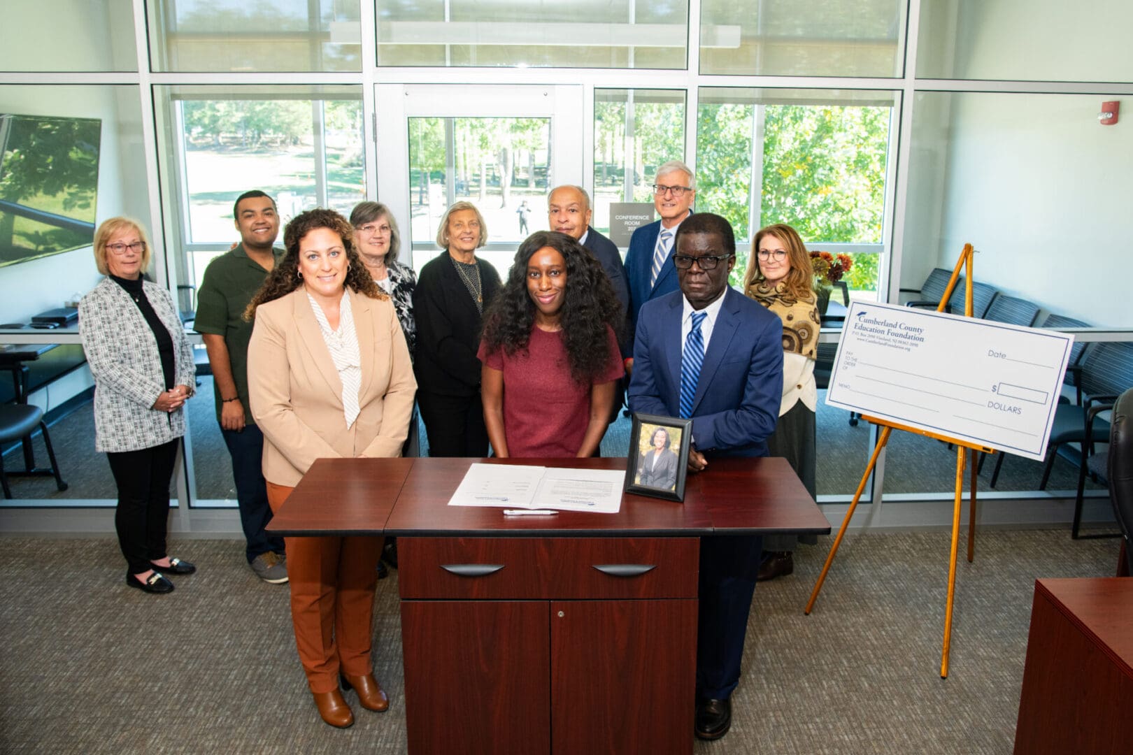 Group photo with oversized check and documents.