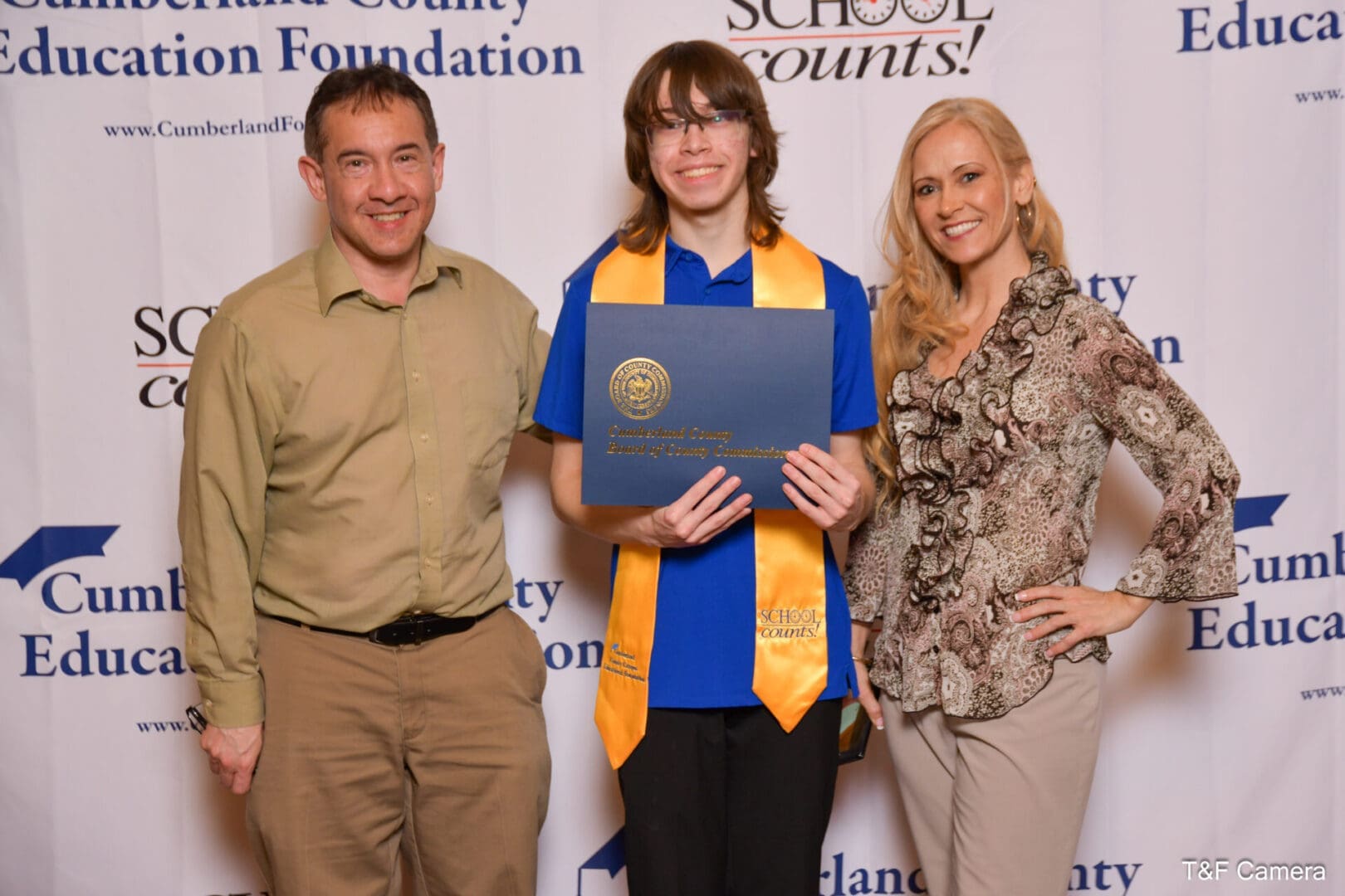 Graduate holding diploma with smiling adults