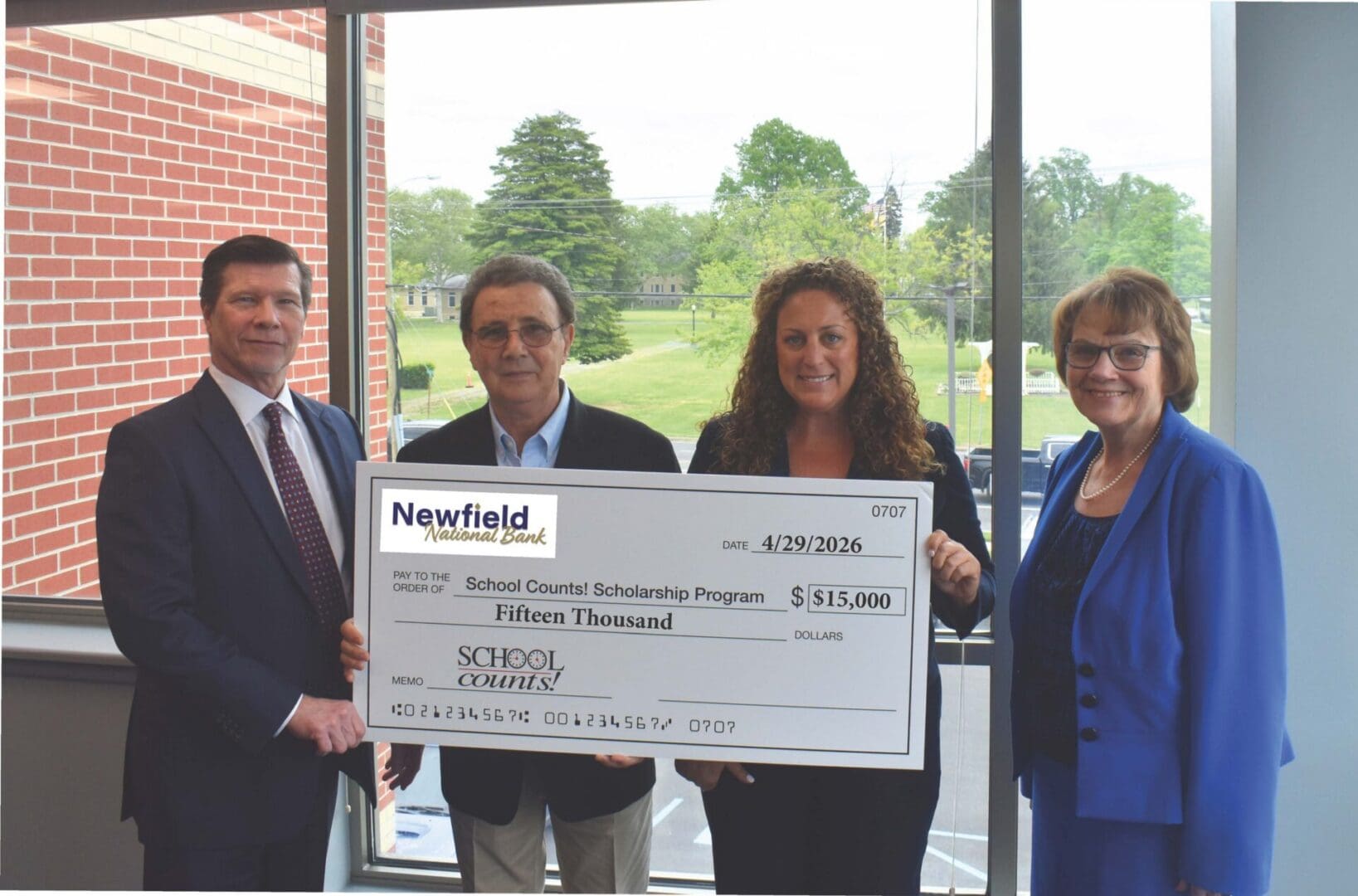 Four people holding oversized donation check